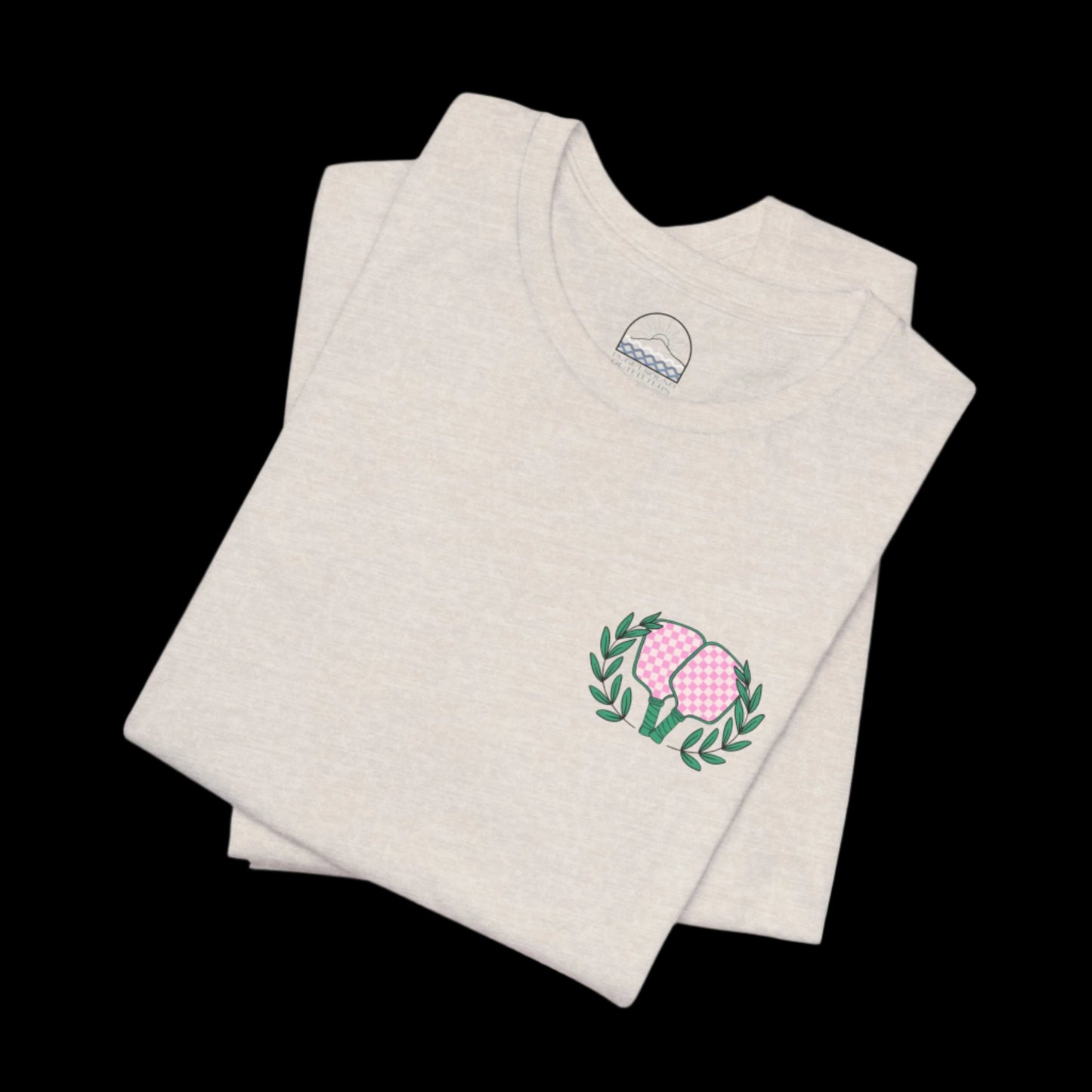 Folded lay of tan unisex pickleball shirt showing front design