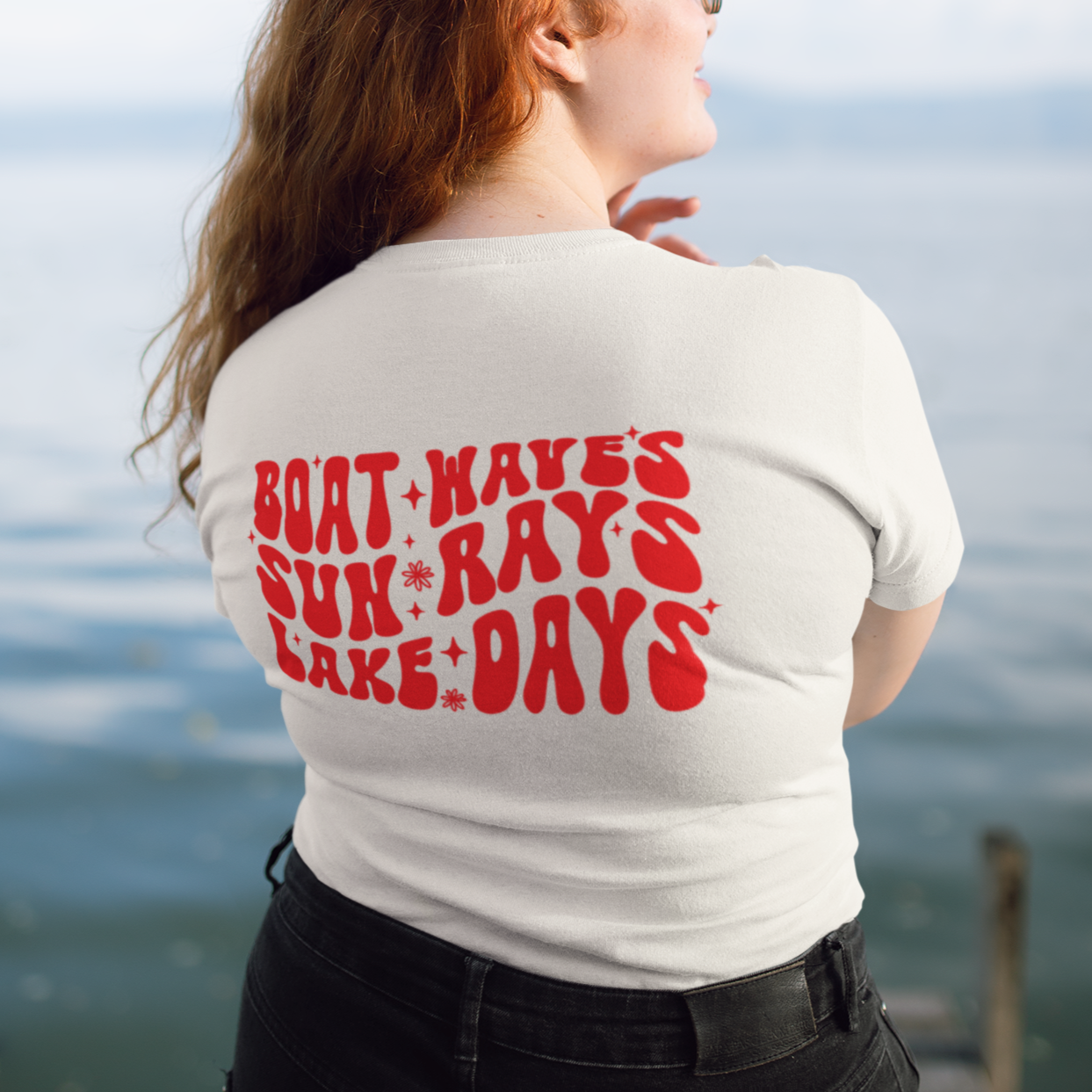Person wearing a vintage boat and lake days t-shirt by the water facing away from camera to show lettering.